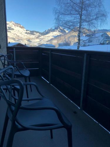 a balcony with two chairs and a view of snow covered mountains at Ferienwohnung nähe Flumserberg Ski Wandergebiet in Filzbach