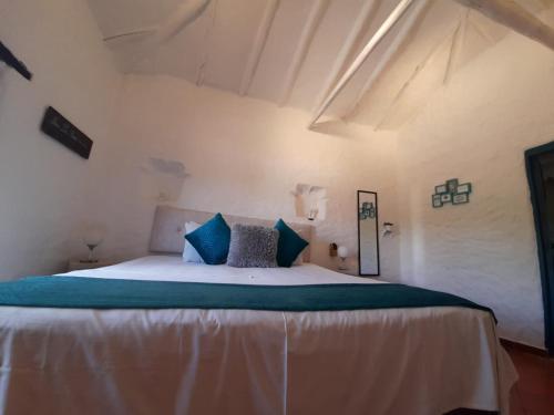 a bedroom with a large bed with blue pillows at Hotel Santos De Piedra - MARANATHA BARICHARA in Barichara