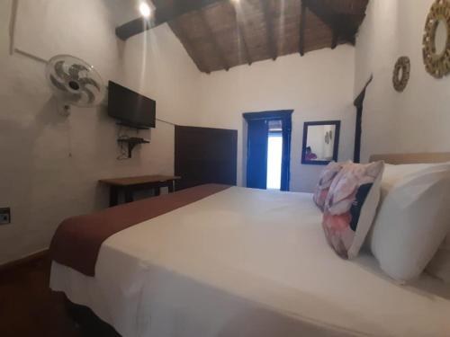 a large white bed in a room with a television at Hotel Santos De Piedra - MARANATHA BARICHARA in Barichara