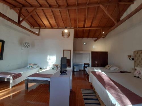 a room with three beds and a tv in it at Hotel Santos De Piedra - MARANATHA BARICHARA in Barichara