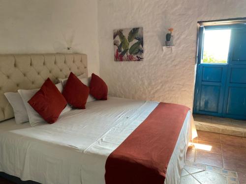 a bedroom with a bed with red pillows and a window at Hotel Santos De Piedra - MARANATHA BARICHARA in Barichara