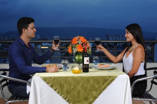 a man and woman sitting at a table with wine glasses at Hotel San José Plaza in Bucaramanga