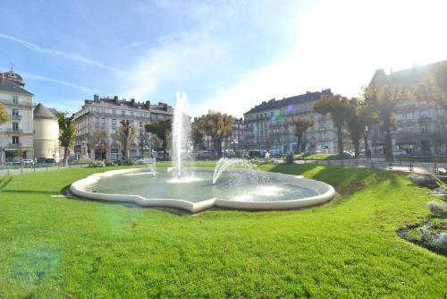 a large fountain in the middle of a grassy area at Hôtel d’Angleterre Grenoble Hyper-Centre in Grenoble