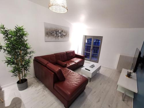 sala de estar con sofá de cuero marrón y mesa en Appartement cosy entièrement équipé en Villeneuve-sur-Lot
