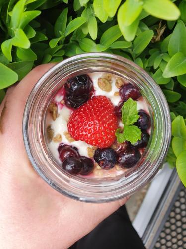 a person holding a glass jar of fruit and yogurt at Dunluce Boutique B&B in Te Anau