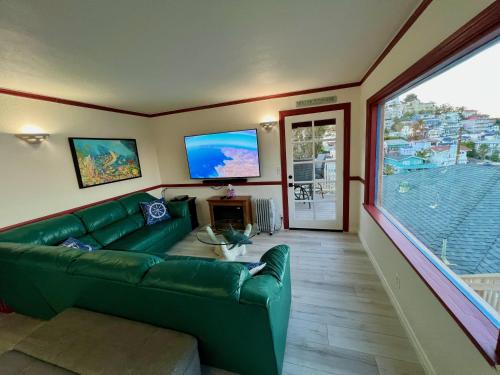 a living room with a green couch and a large window at Catalina Two Bedroom View Home in Avalon