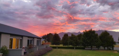 a sunset over a house with mountains in the background at Dunluce Boutique B&B in Te Anau