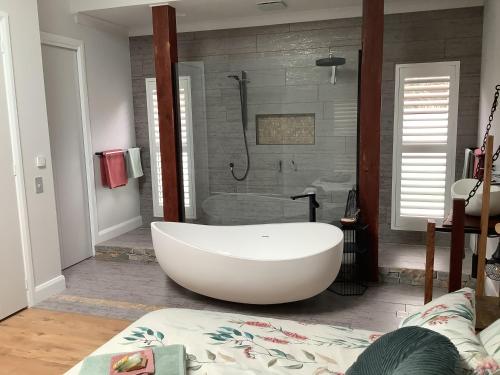 a bathroom with a white tub and a shower at Pericoe Retreat in Dubbo