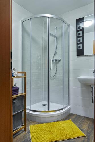 a glass shower in a bathroom with a sink at Apartman Artemis in Bešeňová