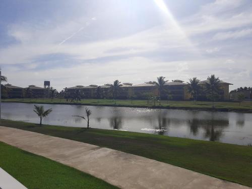 a lake in a park with palm trees and buildings at Apartamento na Praia do Saco - Condomínio Villa das Águas in Estância