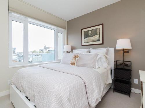 a white bed with a dog sitting on top of it at Sparkling Gem, Brand New Condo In The Heart Of The City in Victoria