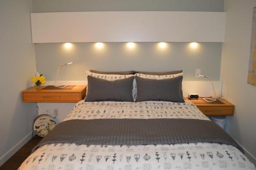 een slaapkamer met een bed met 2 nachtkastjes en 2 lampen bij New Listing, New Building, New New New in Victoria