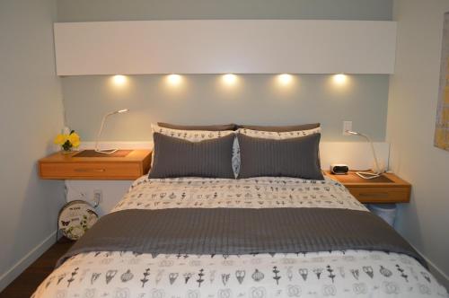 a bedroom with a bed with two night stands and two lamps at Chic 1Br Steps From Chinatown And Harbour in Victoria