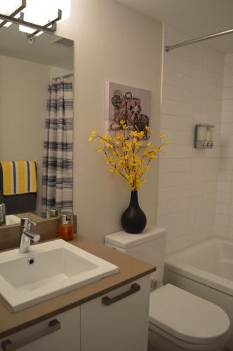a bathroom with a sink and a vase with yellow flowers at Chic 1Br Steps From Chinatown And Harbour in Victoria