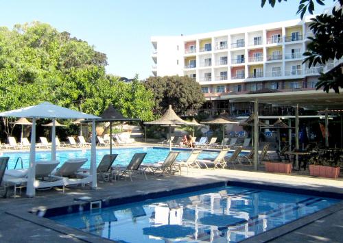 a pool with chairs and umbrellas and a hotel at Marina Hotel in Ayia Napa
