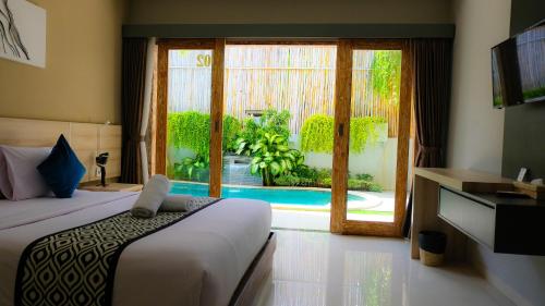 a bedroom with a bed and a view of a pool at Rusty Seminyak in Seminyak
