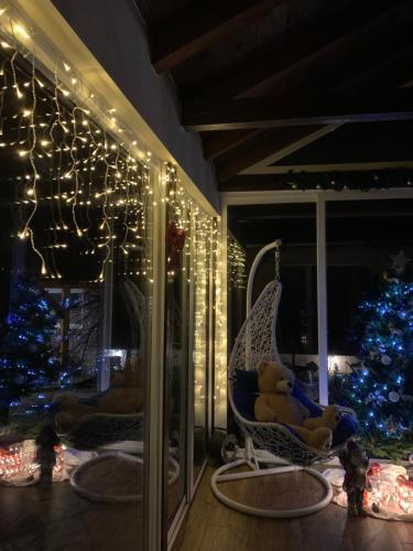 a teddy bear sitting in a chair next to a christmas tree at Vila Impresija, Fruška gora in Novi Sad