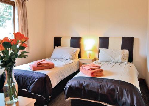 twee bedden in een kamer met een vaas met handdoeken bij Heartsease Lodges in Llanbister