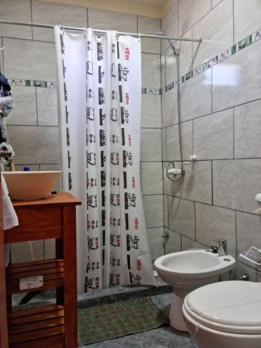 a bathroom with a toilet and a shower curtain at ITURANCH in Ituzaingó