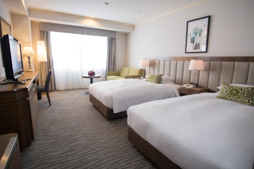 a hotel room with two beds and a television at Nagoya Tokyu Hotel in Nagoya