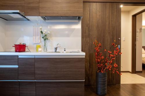 uma cozinha com um lavatório e um vaso com flores em Miidokoro House Hotel em Sapporo
