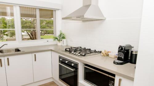 a kitchen with white cabinets and a stove top oven at McMillans of Metung Coastal Resort in Metung