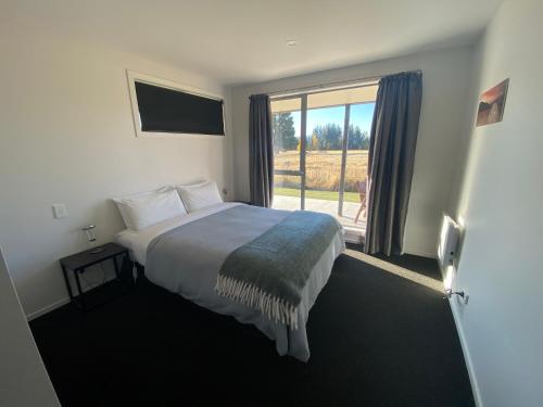 a bedroom with a bed and a large window at Macaulay House in Lake Tekapo