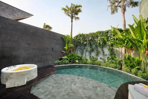 a swimming pool with a bath tub in a garden at Astera Luxury Resort & Spa Canggu by Ini Vie Hospitality in Canggu