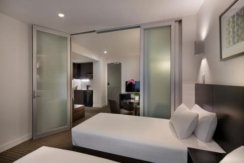 a bedroom with a white bed and a living room at Causeway 353 Hotel in Melbourne