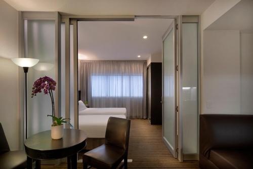 a hotel room with a table and a bedroom at Causeway 353 Hotel in Melbourne