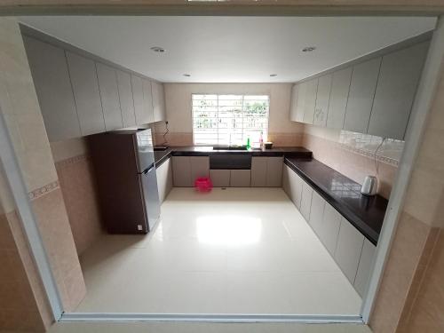 een lege keuken met witte kasten en een koelkast bij Sunny Homestay Kuching - LANDED 14 PAX in Kuching