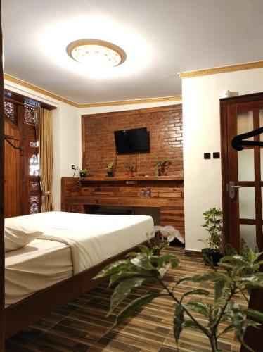 a bedroom with a bed and a flat screen tv at VILLA OPA DOEL YOGYAKARTA in Yogyakarta