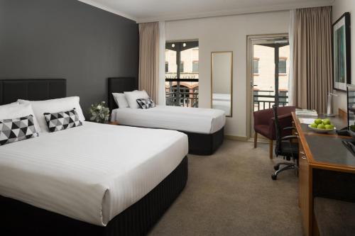 a hotel room with two beds and a desk at Esplanade Hotel Fremantle - by Rydges in Fremantle