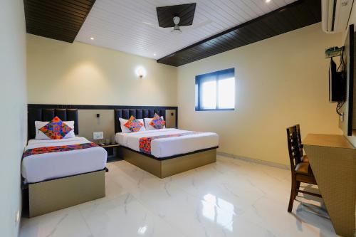 a bedroom with two beds and a desk and a window at FabHotel Prime Land - Nr BKC in Mumbai