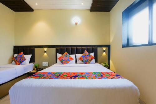 a bedroom with a large white bed with colorful pillows at FabExpress Prime Land in Mumbai