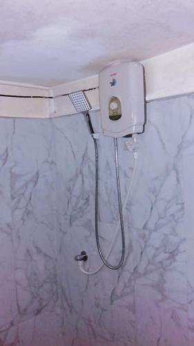 a shower in a bathroom with a white wall at Villa DeLorenta in Anuradhapura
