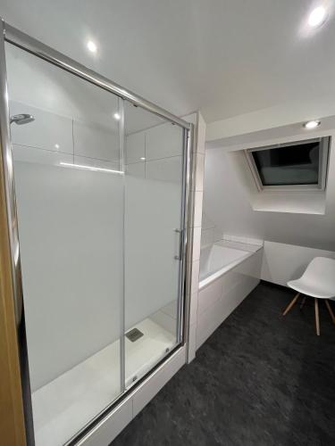 - une douche en verre dans une chambre avec une chaise dans l'établissement Le Ruisseau à Bussang Htes Vosges tout confort, à Bussang