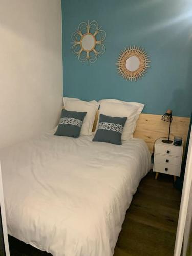 - une chambre avec un lit blanc et un miroir mural dans l'établissement Chaleureux appartement face au Port Sta Lucia, tout à pieds, wifi, à Saint-Raphaël