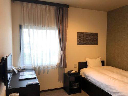 a bedroom with a bed and a desk with a window at HOTEL COLLECT in Sakai