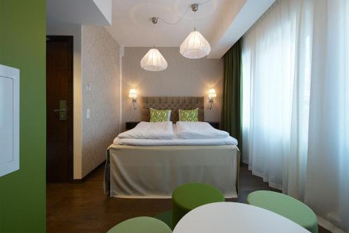 a bedroom with a bed with green chairs and lights at Best Western Hotel Akersberga in Åkersberga