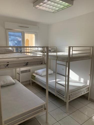 une chambre avec trois lits superposés et une fenêtre dans l'établissement Maison entière avec terrasse barbecue et jardin, à Nîmes