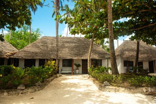 a house with a thatched roof and palm trees at Poa Poa Bungalows in Kiwengwa