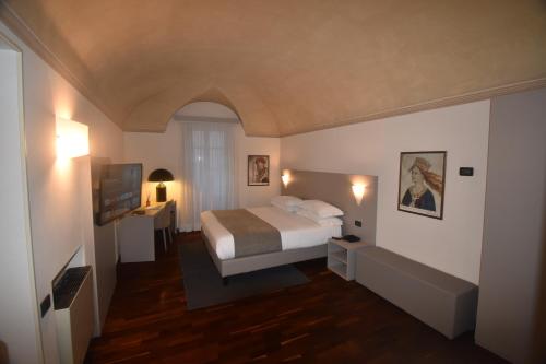 - une chambre avec un lit et une télévision dans l'établissement Hotel Boutique Antiche Mura, à Saluces