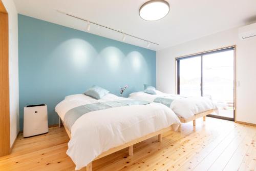 two beds in a room with blue walls at オーシャンヴィラ鳴門-Ocean Villa Naruto- in Naruto