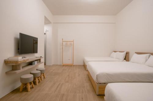 a hotel room with two beds and a television at 澎湖逸軒居民宿 in Huxi