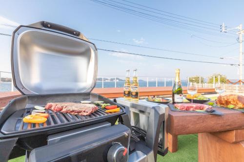 a grill with meat and vegetables and bottles of beer at オーシャンヴィラ鳴門-Ocean Villa Naruto- in Naruto