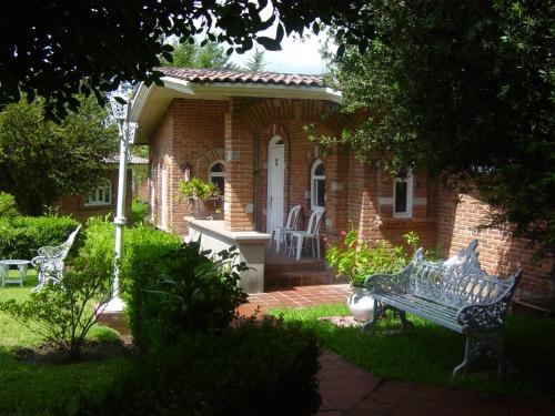a brick house with a bench in the yard at Hotel Villa Monarca Inn in Zitácuaro