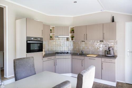a kitchen with white cabinets and a table and chairs at luxe cottage knokke heist in Knokke-Heist
