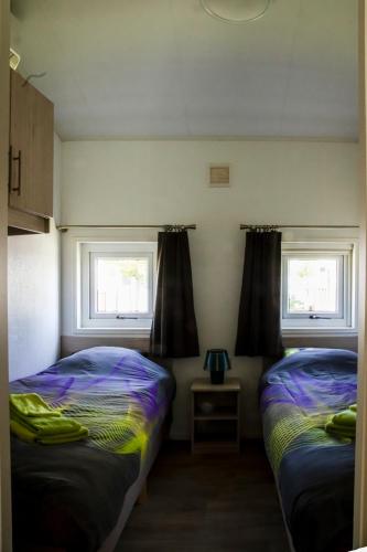 two beds in a room with two windows at luxe cottage knokke heist in Knokke-Heist