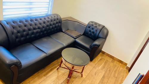 a black leather couch in a living room with a table at Thenmala Hormuz Inn in Kolattupuzha